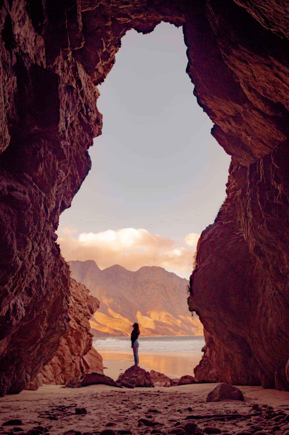 A lone figure stands on a rock formation with their back to the viewer