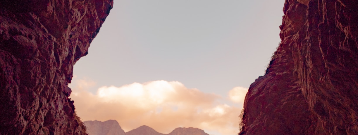 silhouette of person standing on top of rock during daytime