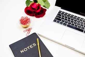 Elegant workspace with a sleek black and rose gold laptop and a stylish notebook.