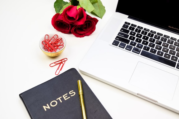 Elegant workspace with a sleek black and rose gold laptop and a stylish notebook.