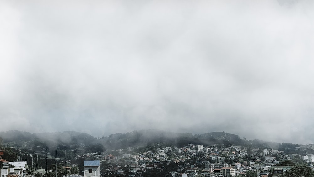 fotografia aerea di case ed edifici che osservano la montagna in una giornata nebbiosa