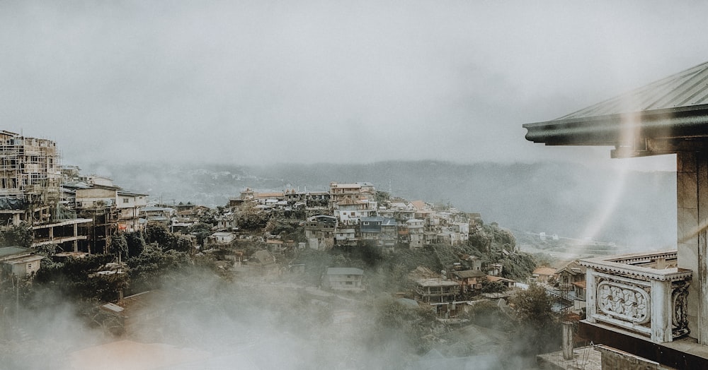 aerial photography of houses and buildings viewing mountain in foggy day