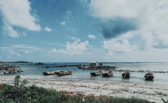 grey wooden boats on body of water during daytime in Bintan Indonesia