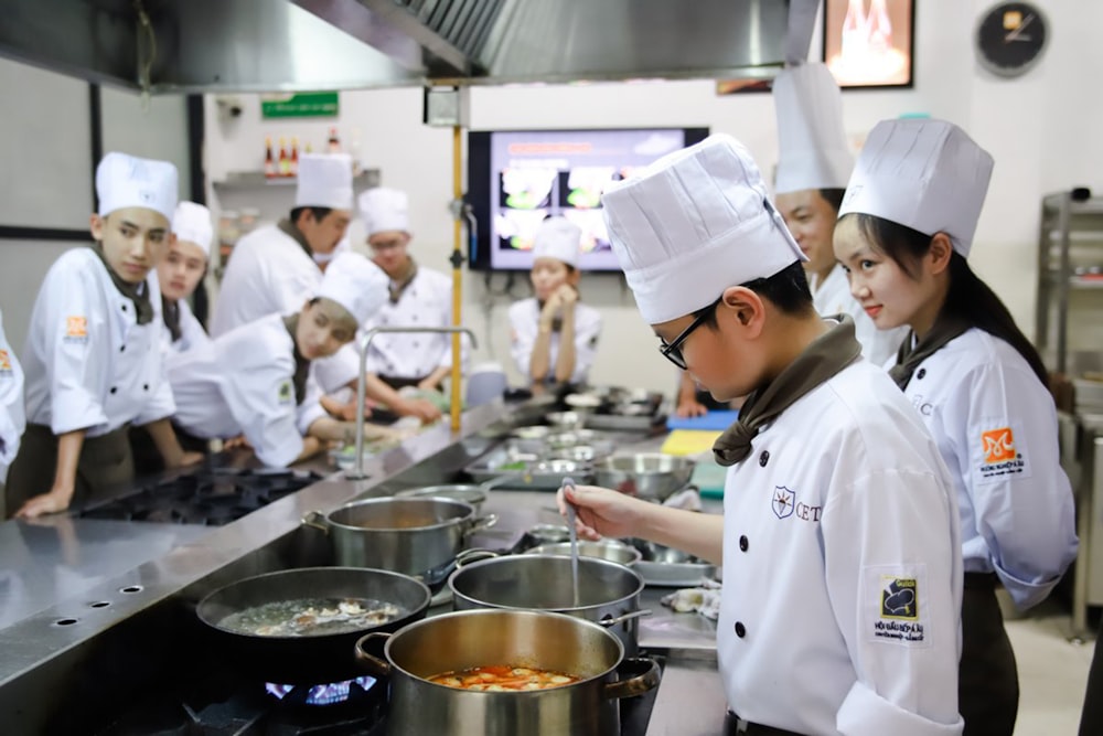 chefs standing near cooking pots inside kitchen