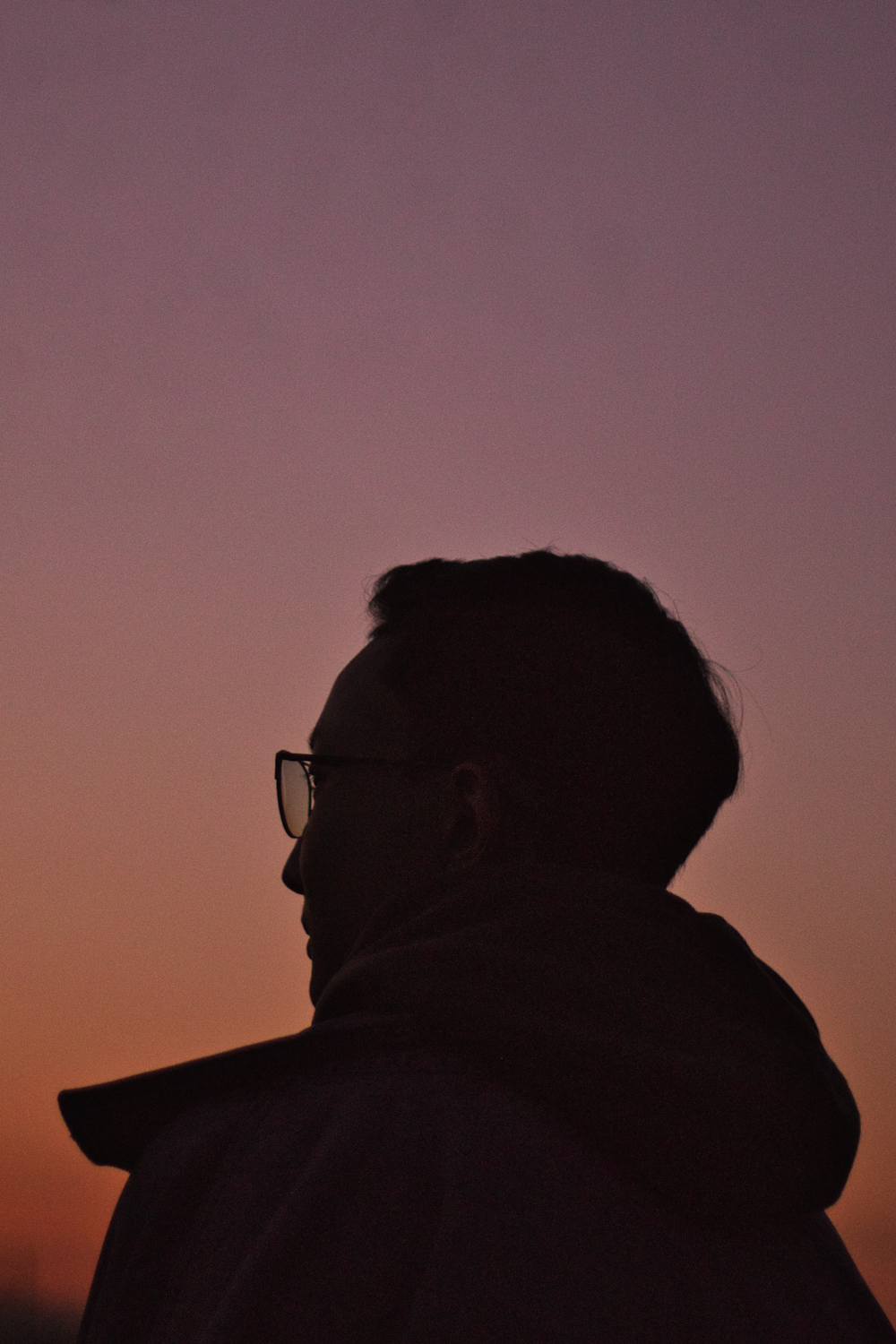 a man with glasses is looking at the sky