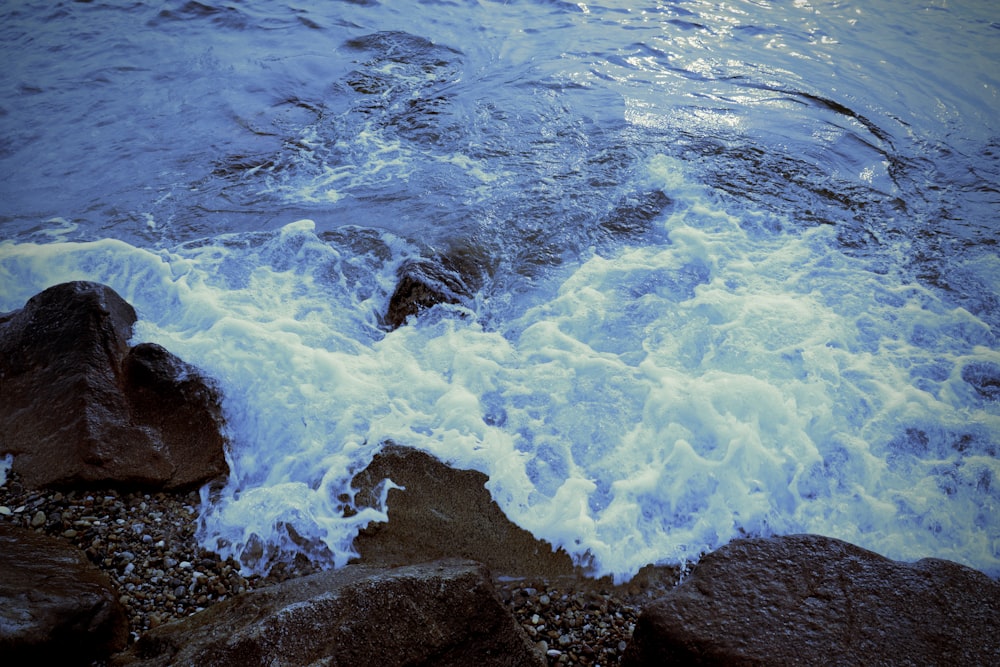 wave splashing on rocks during daytime