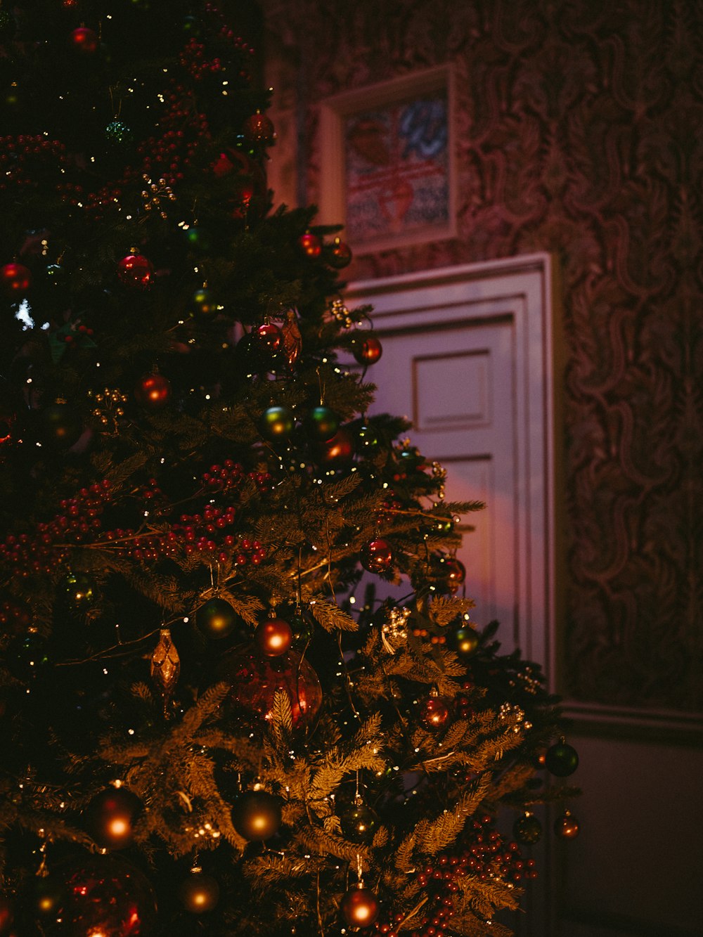 baubles and string lights filled Christmas tree by close door
