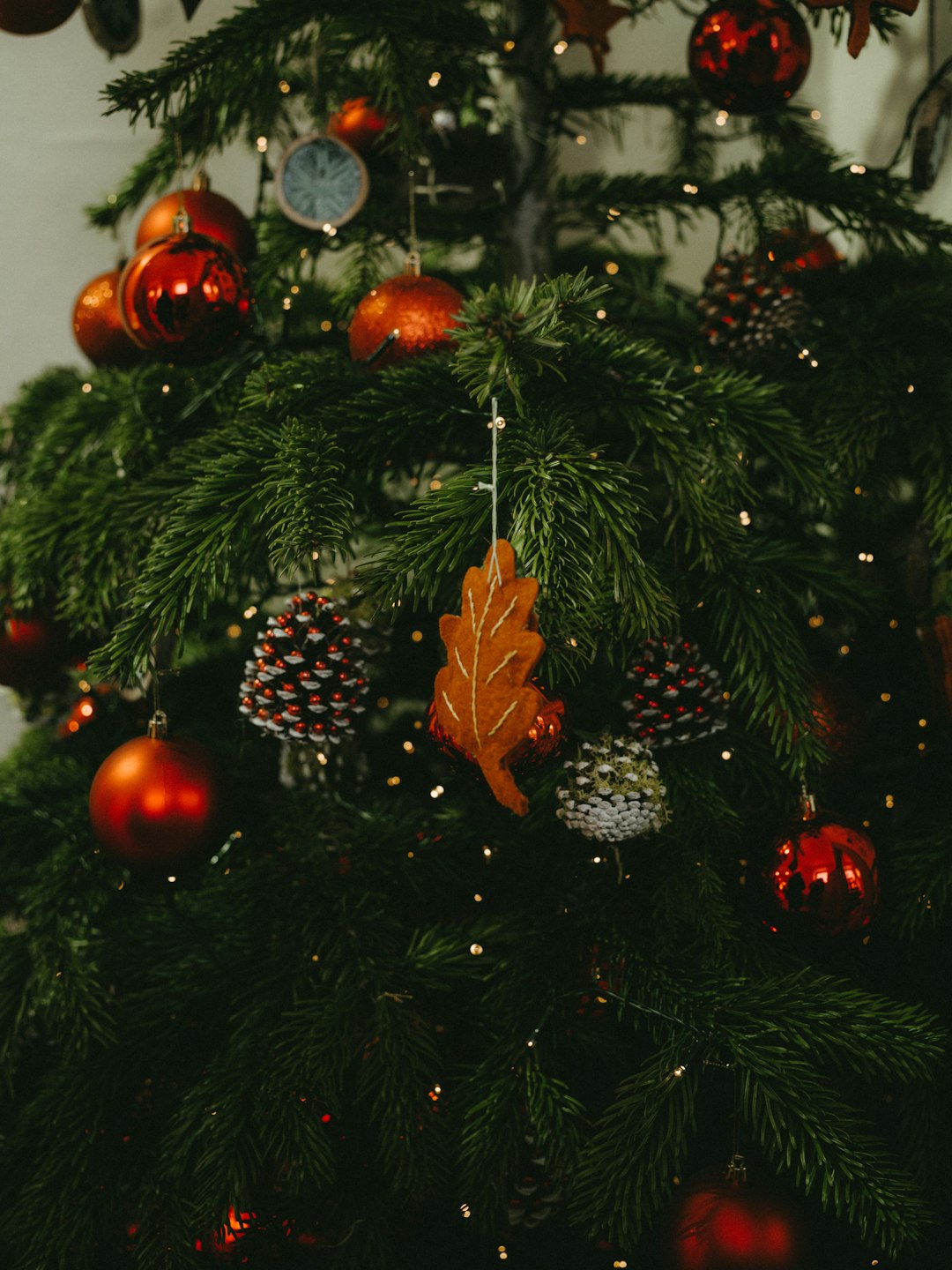 closeup photo of Christmas tree with baubles, pine cones, and string lights