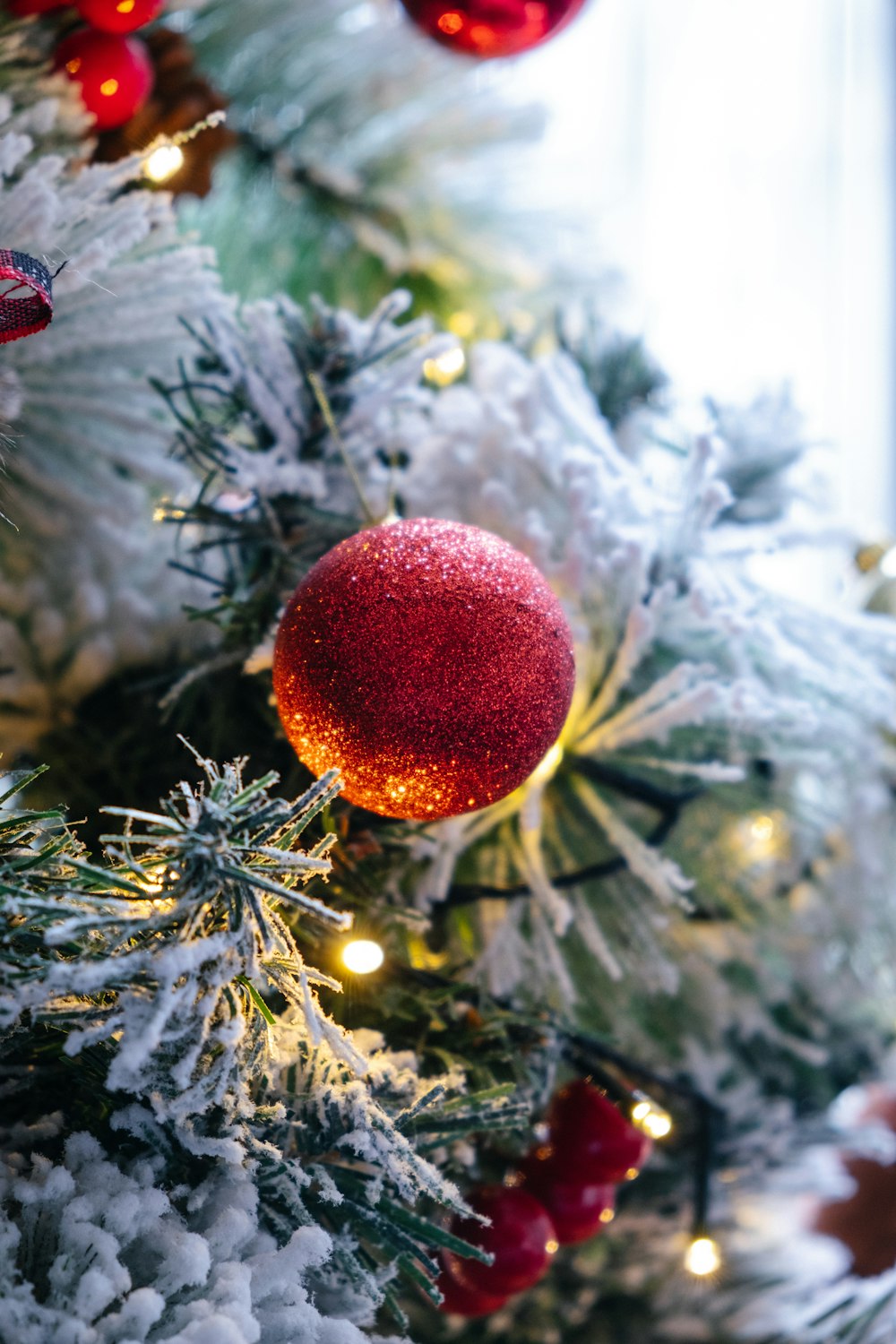 macro photography of red bauble and lighted string lights on green Christmas tree