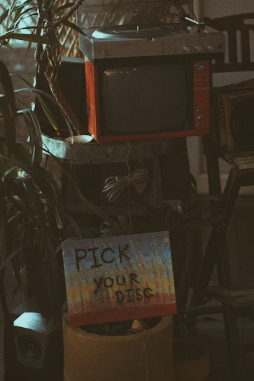 A cozy living room scene with a vintage DVD player and a stack of classic movie DVDs on a wooden shelf.
