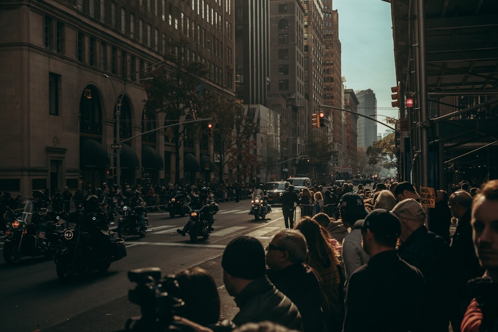 motorcyclist on road while crowd on sidewalk at daytime