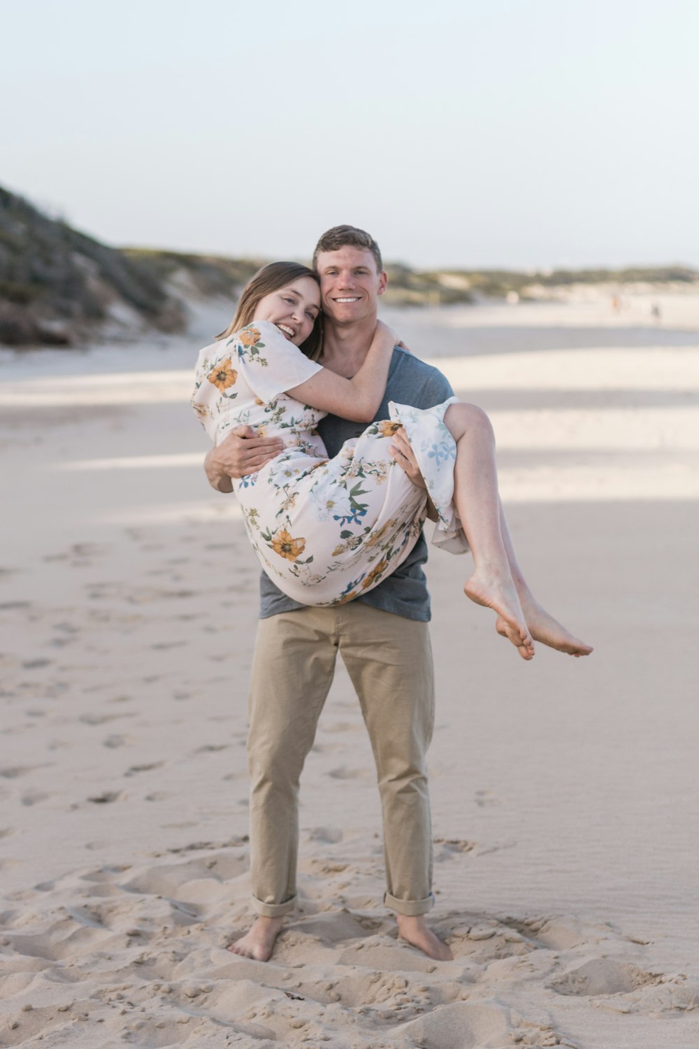 man carrying woman on sand field