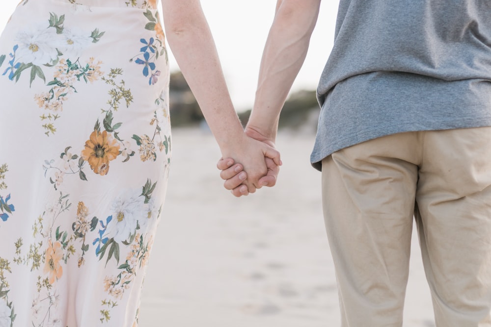 Mann und Frau halten Händchen auf Sandfeld