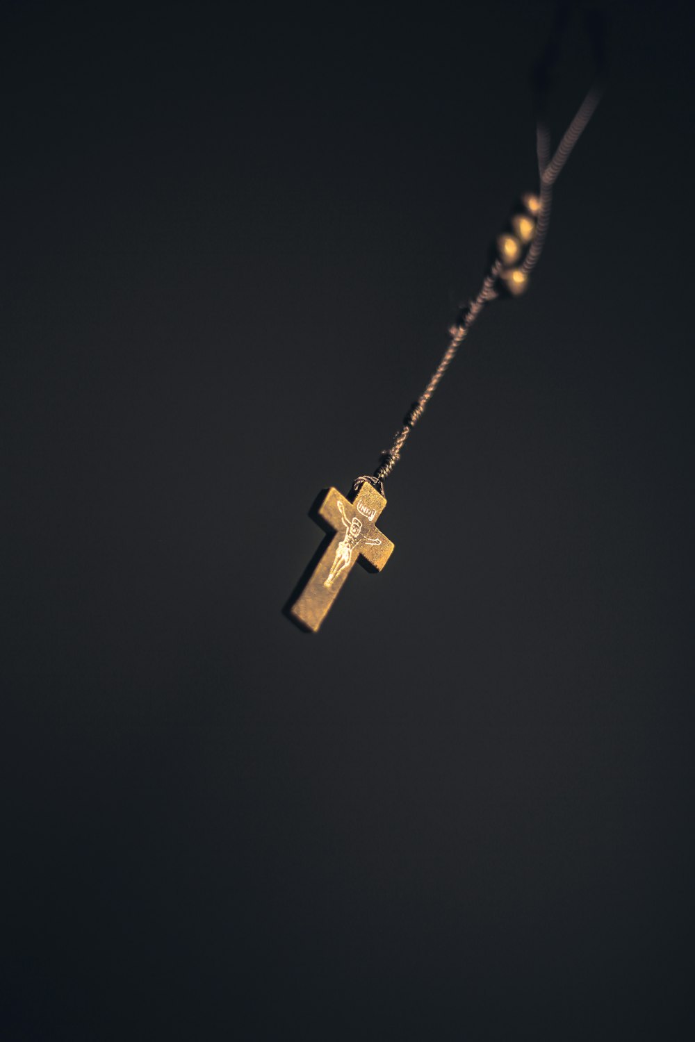 gold-colored cross pendant on black background