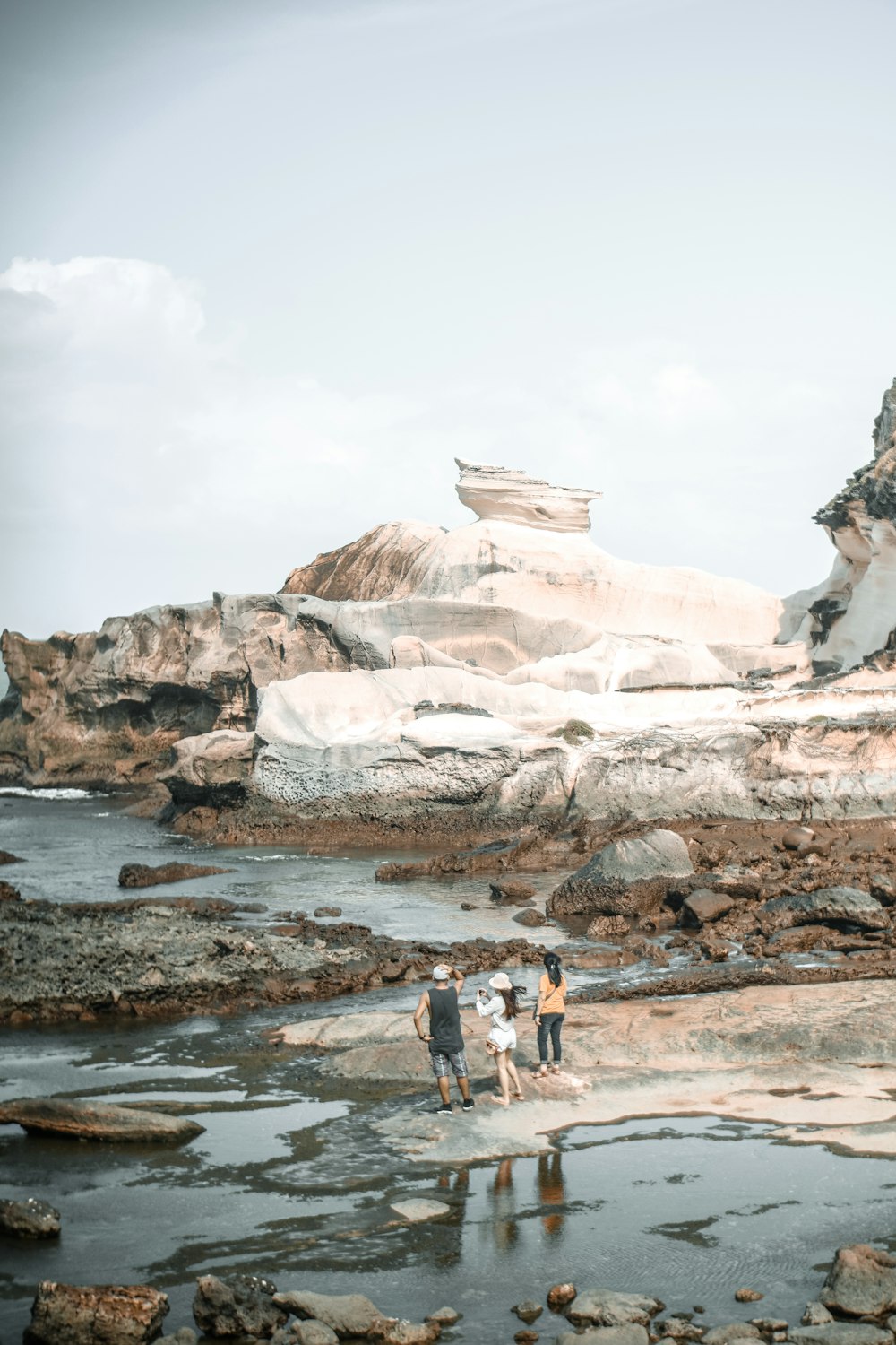 three women standing beside body of water