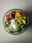 A vibrant, colorful salad bowl topped with fresh greens, cherry tomatoes, and avocado slices.