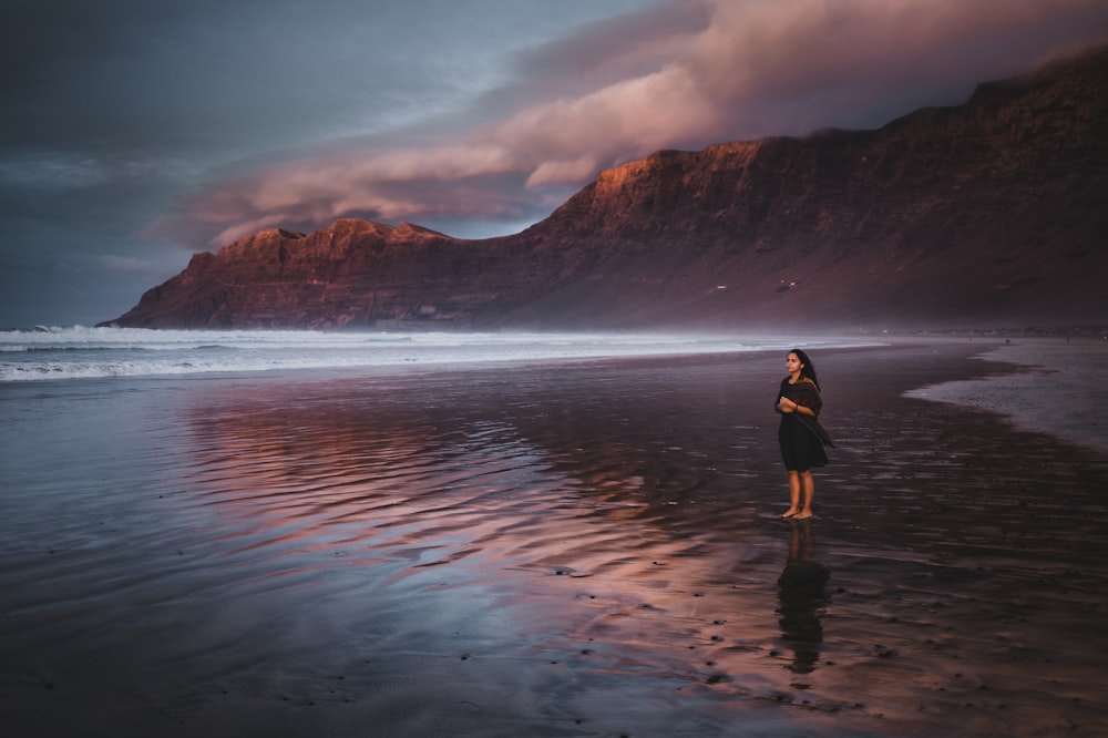 a woman standing on a beach next to the ocean