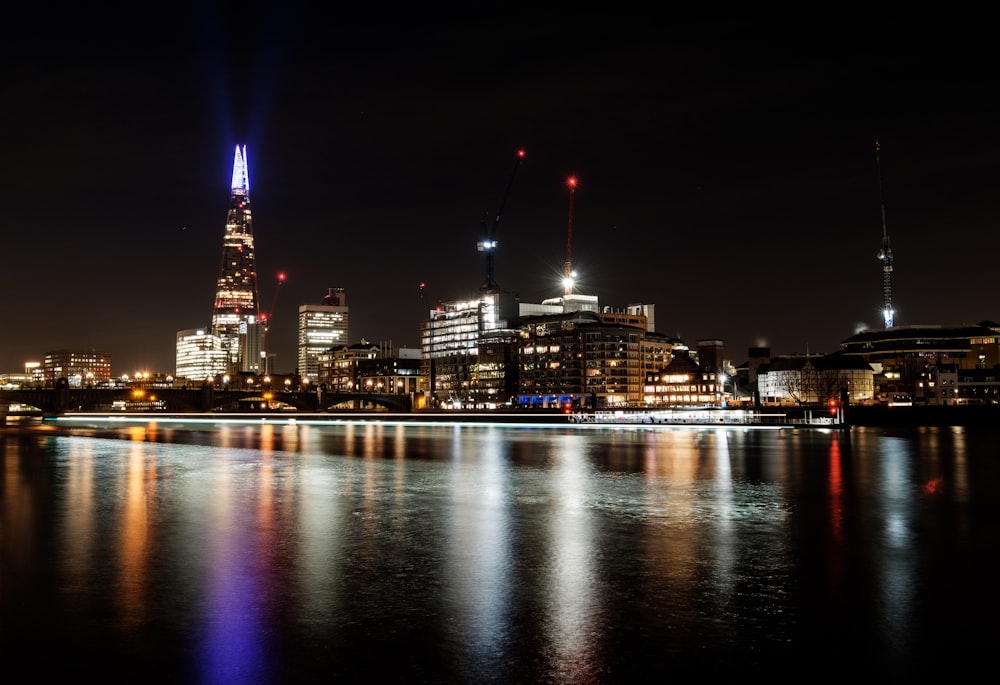 lighted buildings near body of water during night time