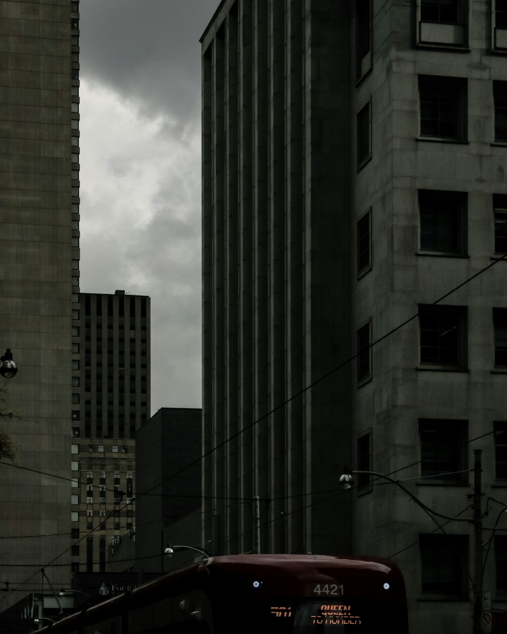 a red bus driving down a street next to tall buildings