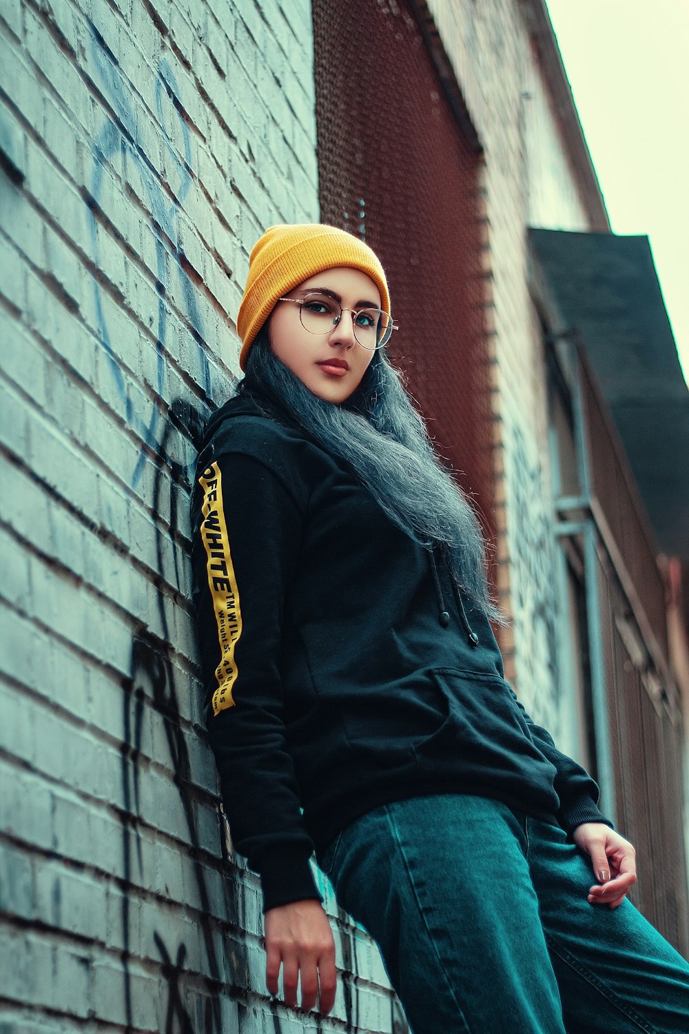 woman wearing black and yellow hoodie beside wall
