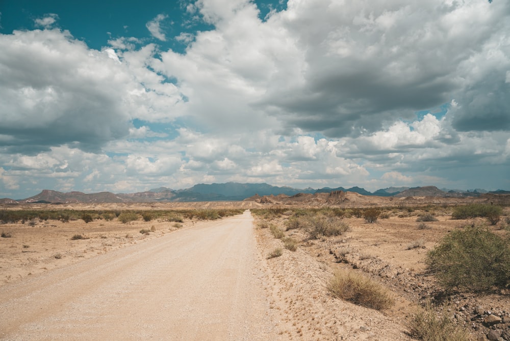 road near desert viewing mountain under white and blue sky