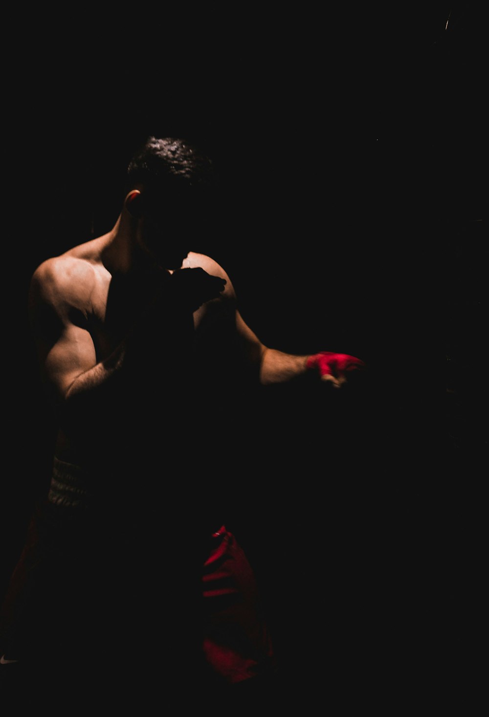 topless man wearing red shorts standing while facing left side