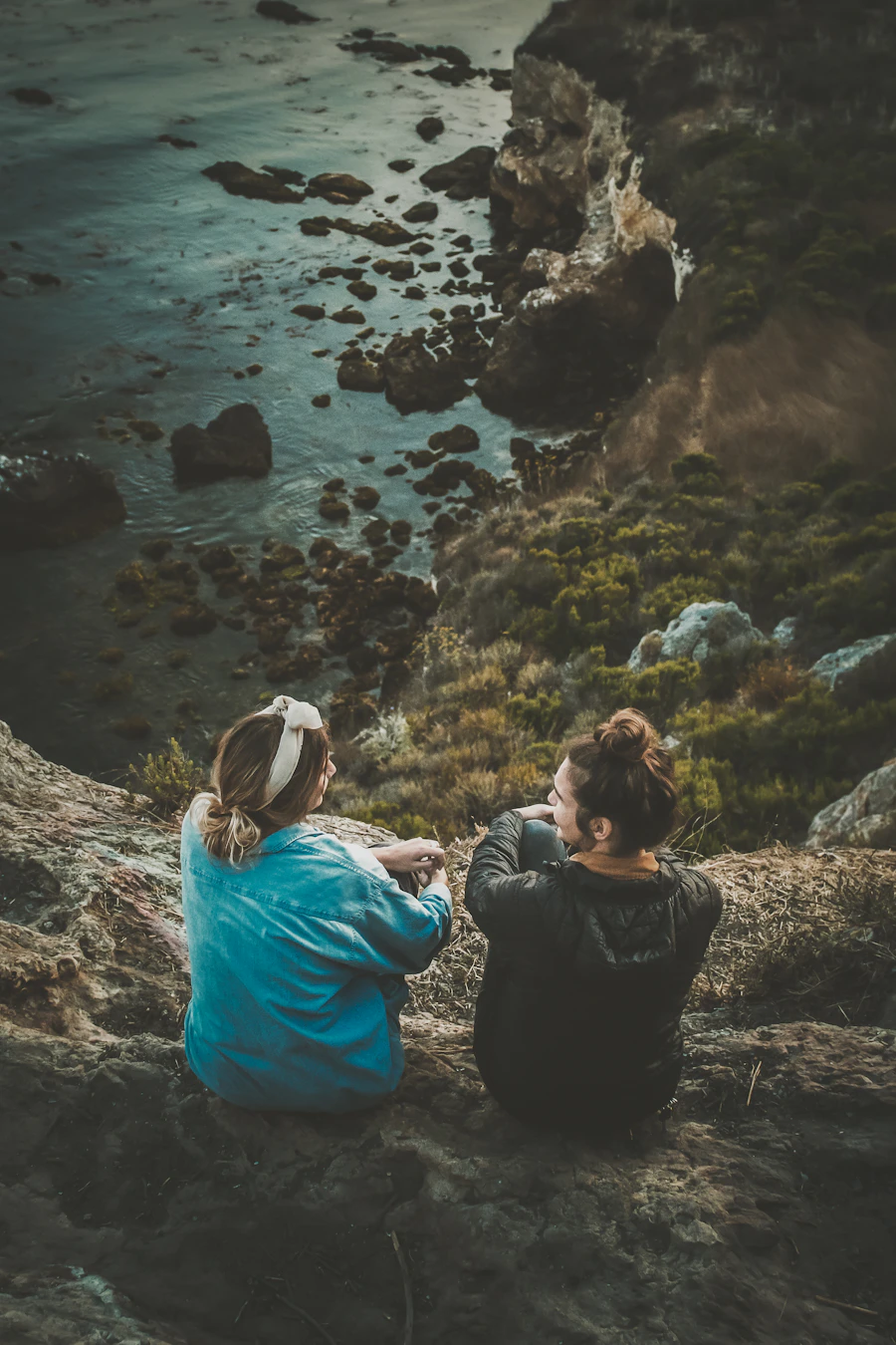 Two women sitting together on a sea cliff