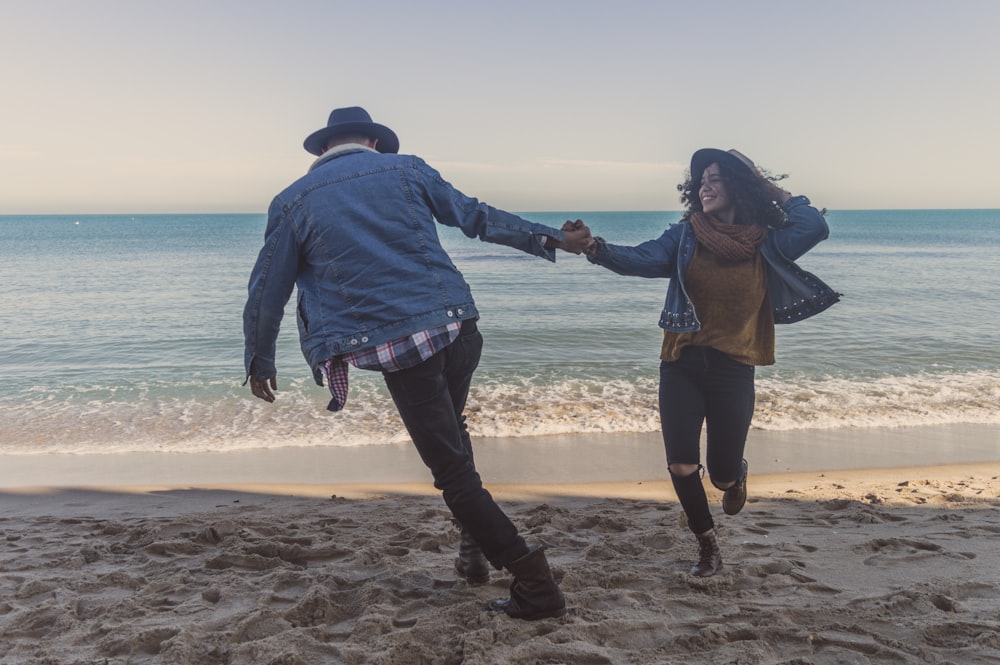 a man and a woman are running on the beach