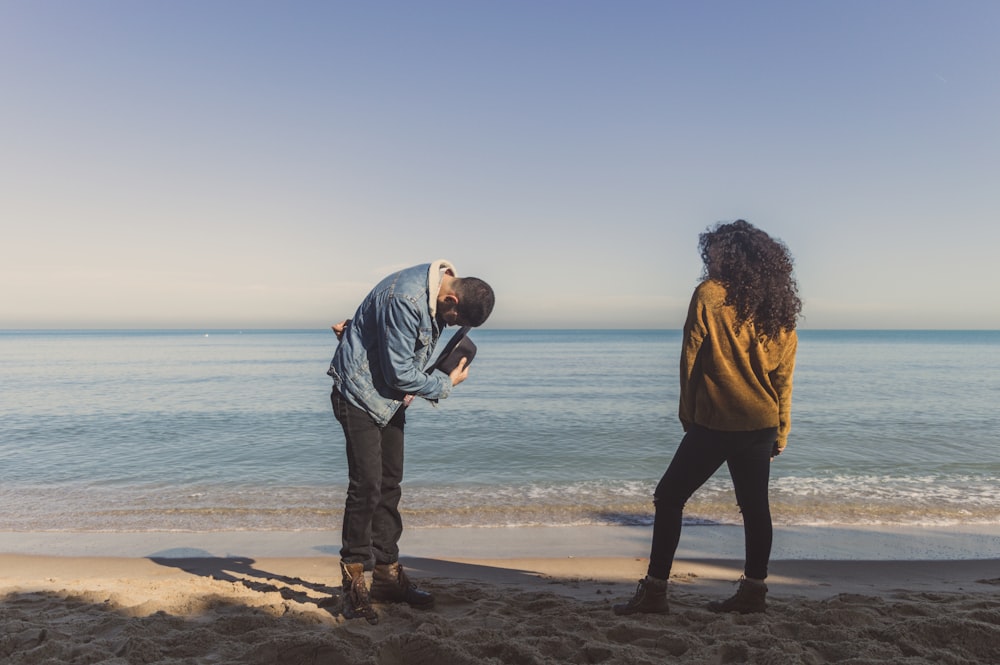 man bowing in front of a woman on seashore during day
