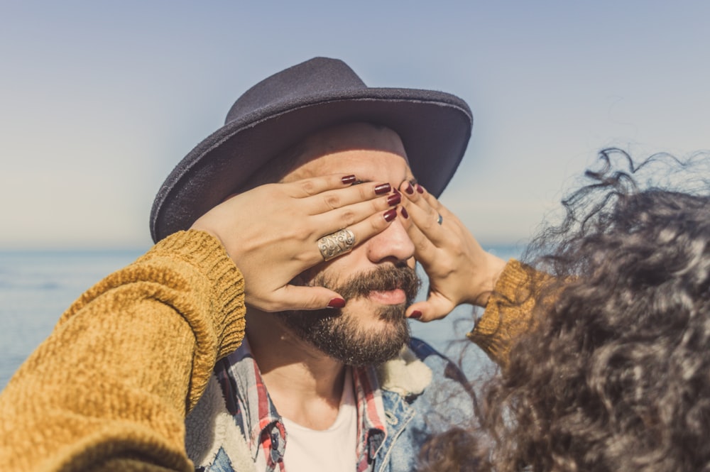 woman covering man's eyes during daytime