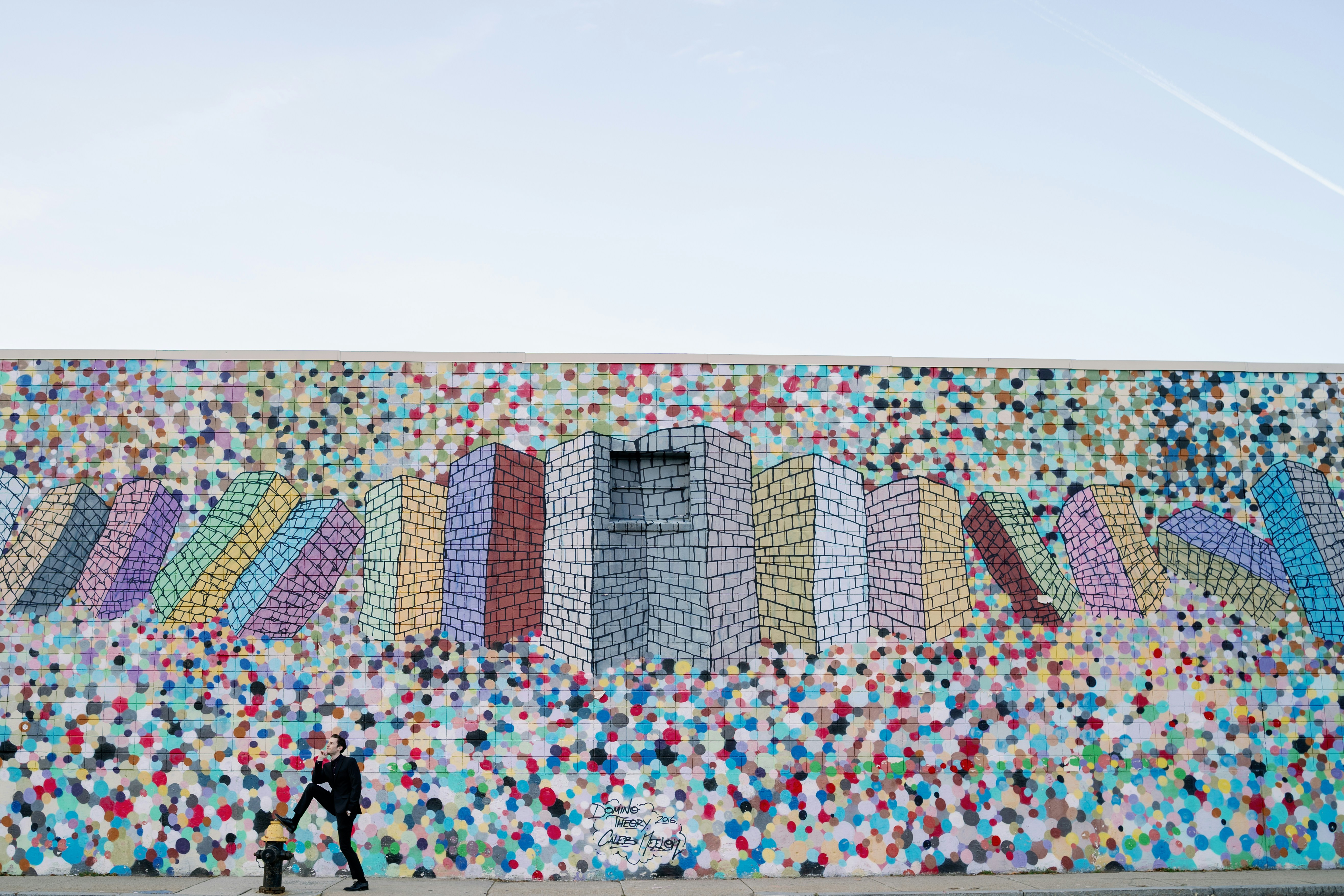 Un homme passant devant un mur avec une peinture murale dessus