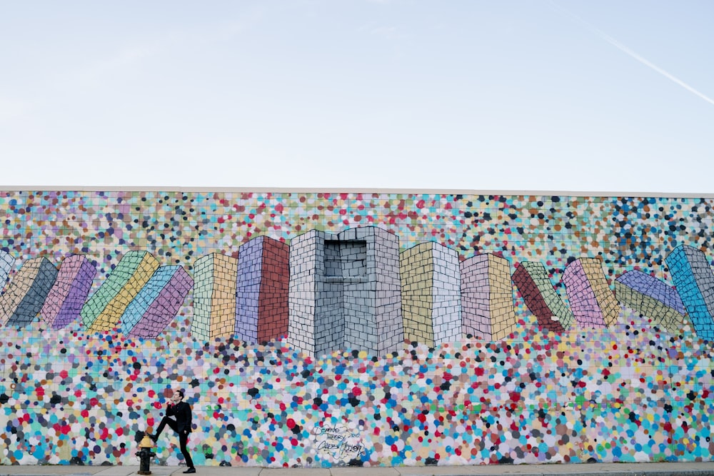 a man walking past a wall with a mural on it