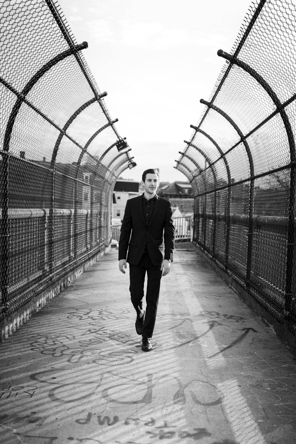 a man in a suit walking across a bridge