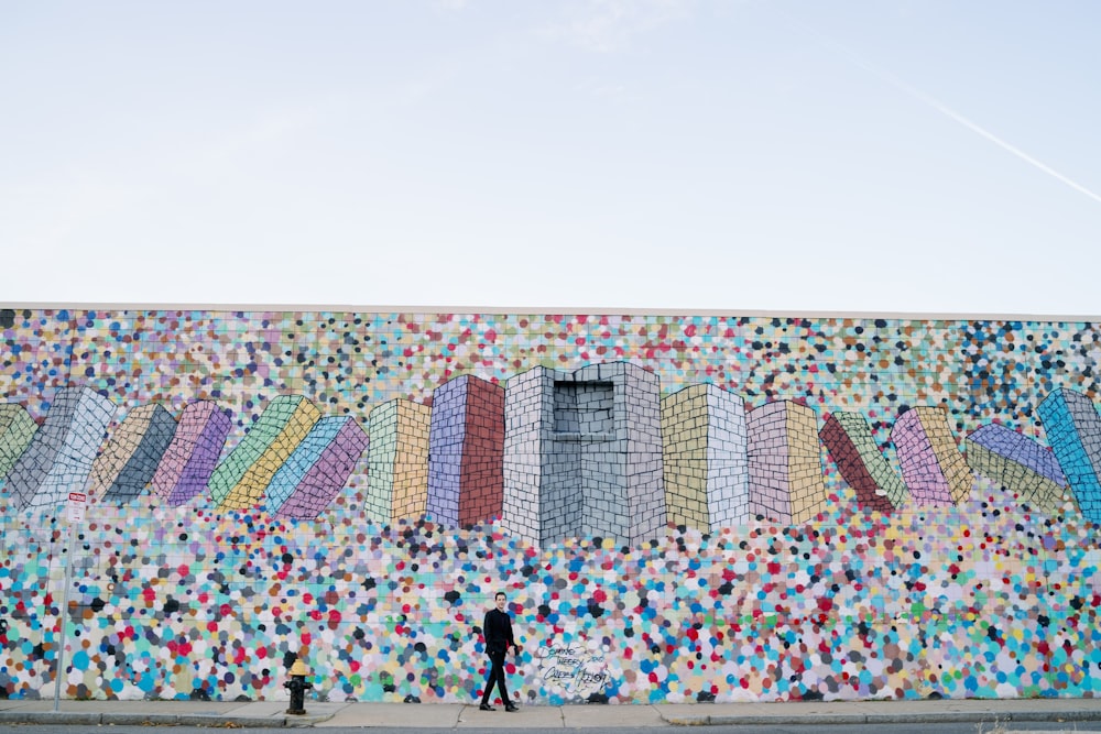 person standing near fire hydrant and wall with mural