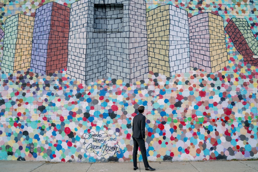 man standing beside multicolored wall