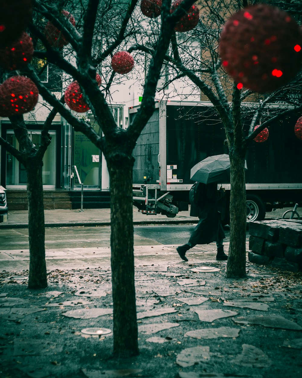 person holding red umbrella walking on sidewalk during daytime