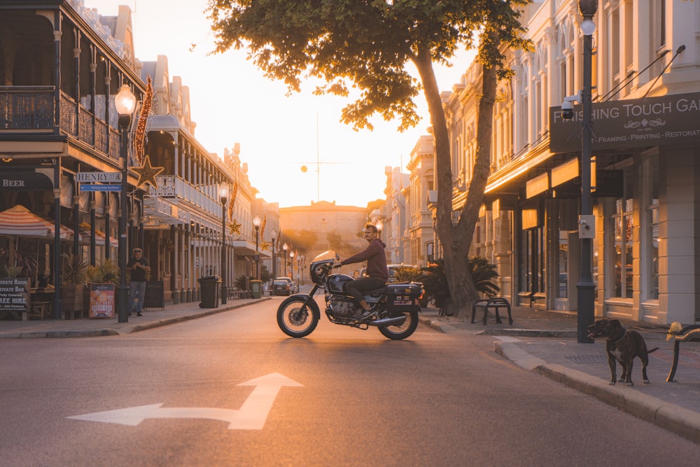 Hombre en motocicleta estándar cerca de un árbol