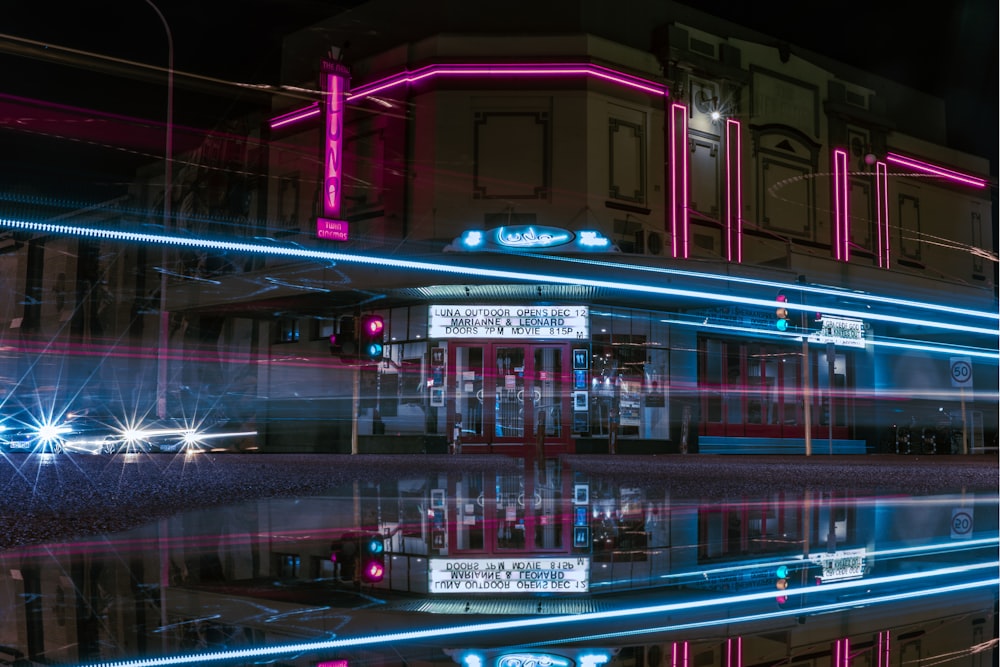 a building with neon lights reflecting in the water