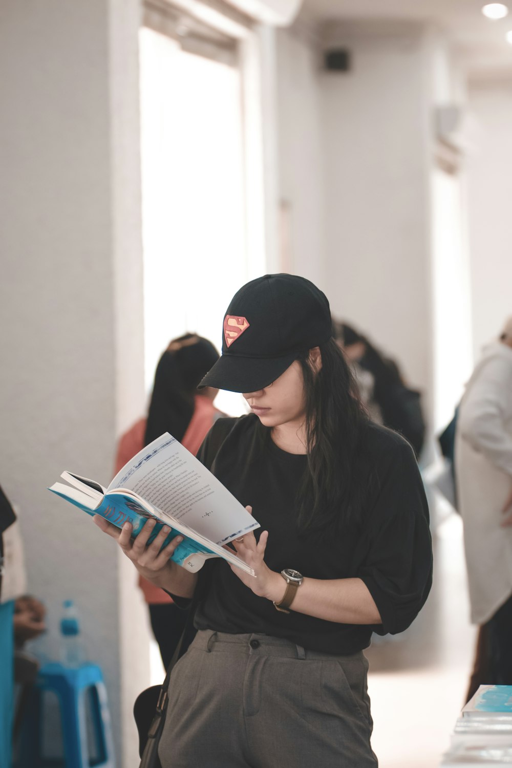 woman standing and reading book near people inside room