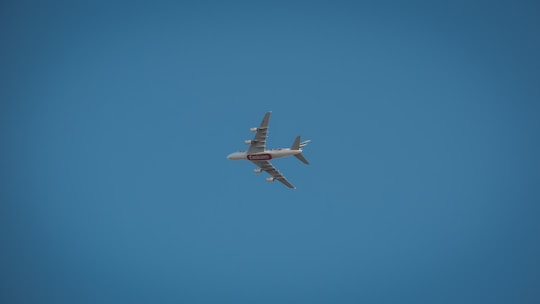 A large commercial airplane, possibly an Airbus, is flying against a clear blue sky. The aircraft is seen from below and is prominently marked with airline branding.
