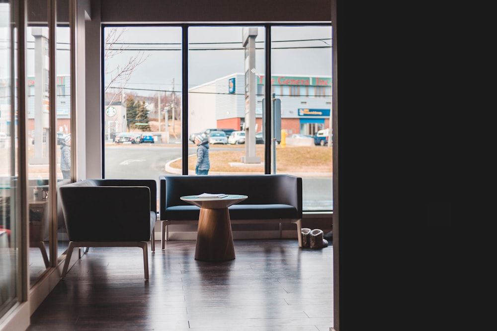 round brown wooden table infront of black sofa