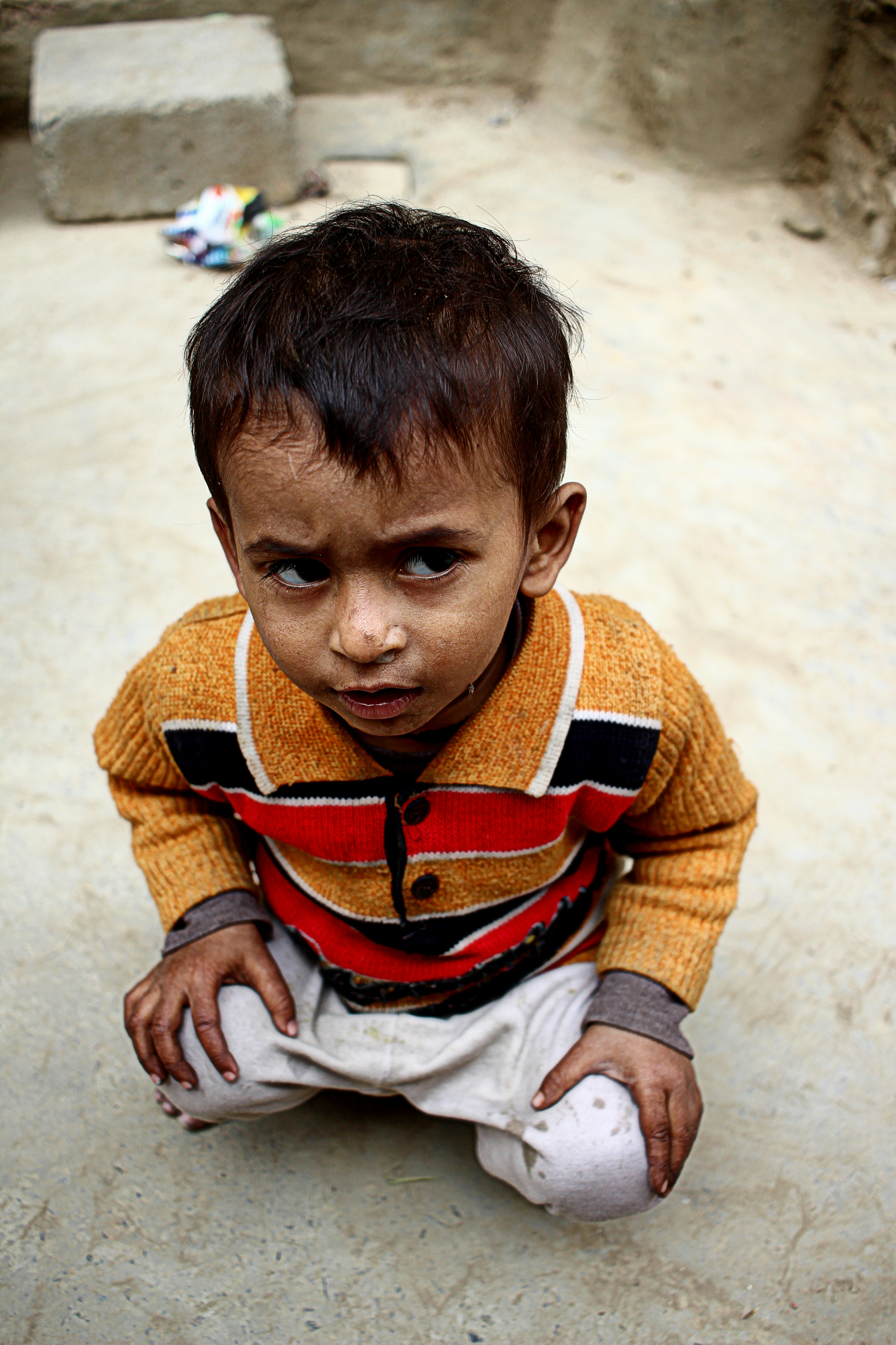 boy in orange and black sweater sitting on floor