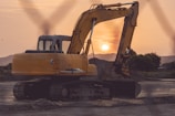 A heavy excavator digging earth at a construction site during sunset.