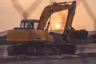 Sunset view of a demolition site with dust settling and machinery parked.