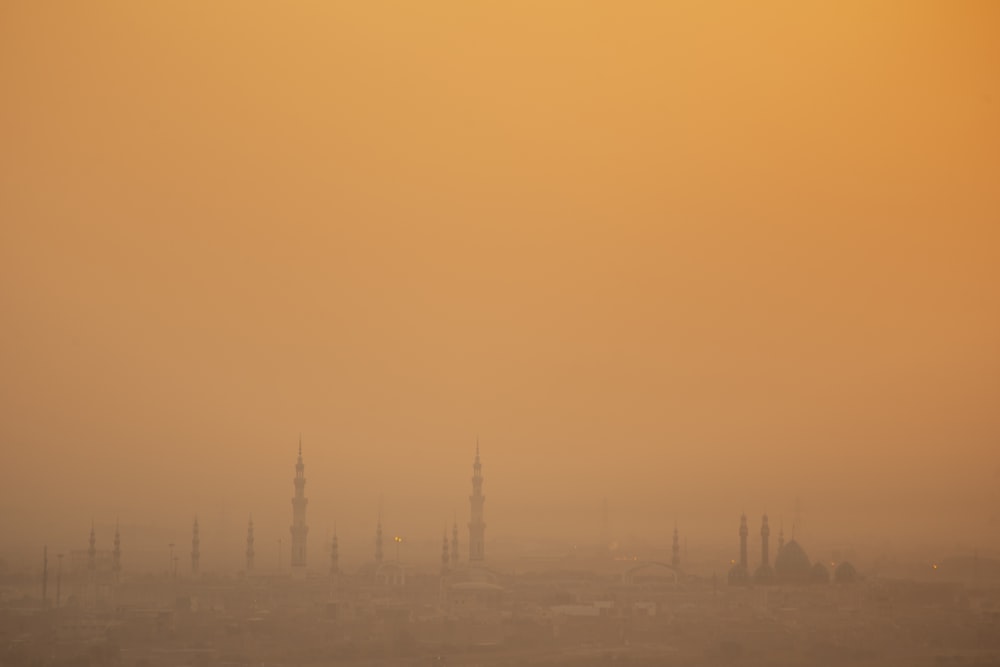 a foggy city skyline with a plane flying in the sky