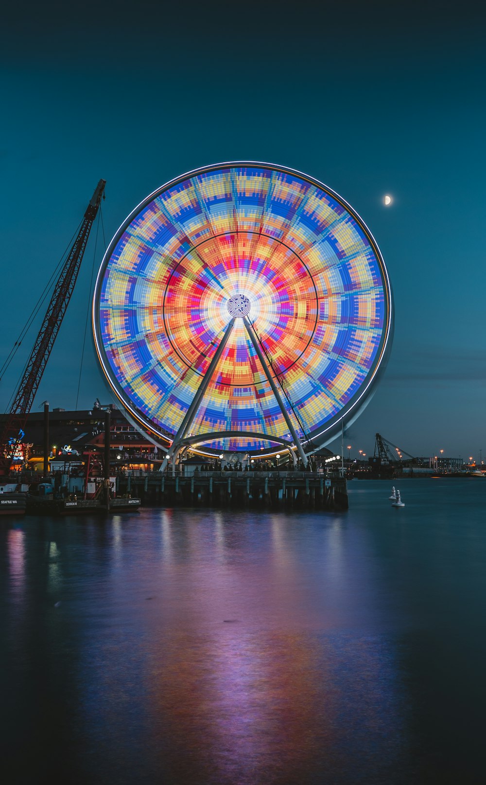 multicolored ferris wheel in amusement park near body of water during night time