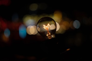 Close-up of a sleek smart bulb glowing softly with neon cyan light against a deep midnight blue background.