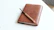 Close-up of a worn journal and a pen resting on a slate black surface with gold accents.