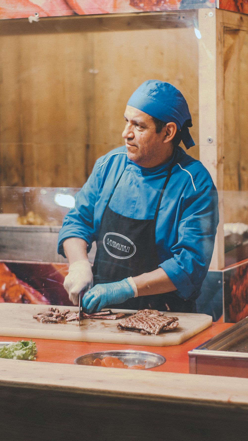 man wearing apron chopping meat