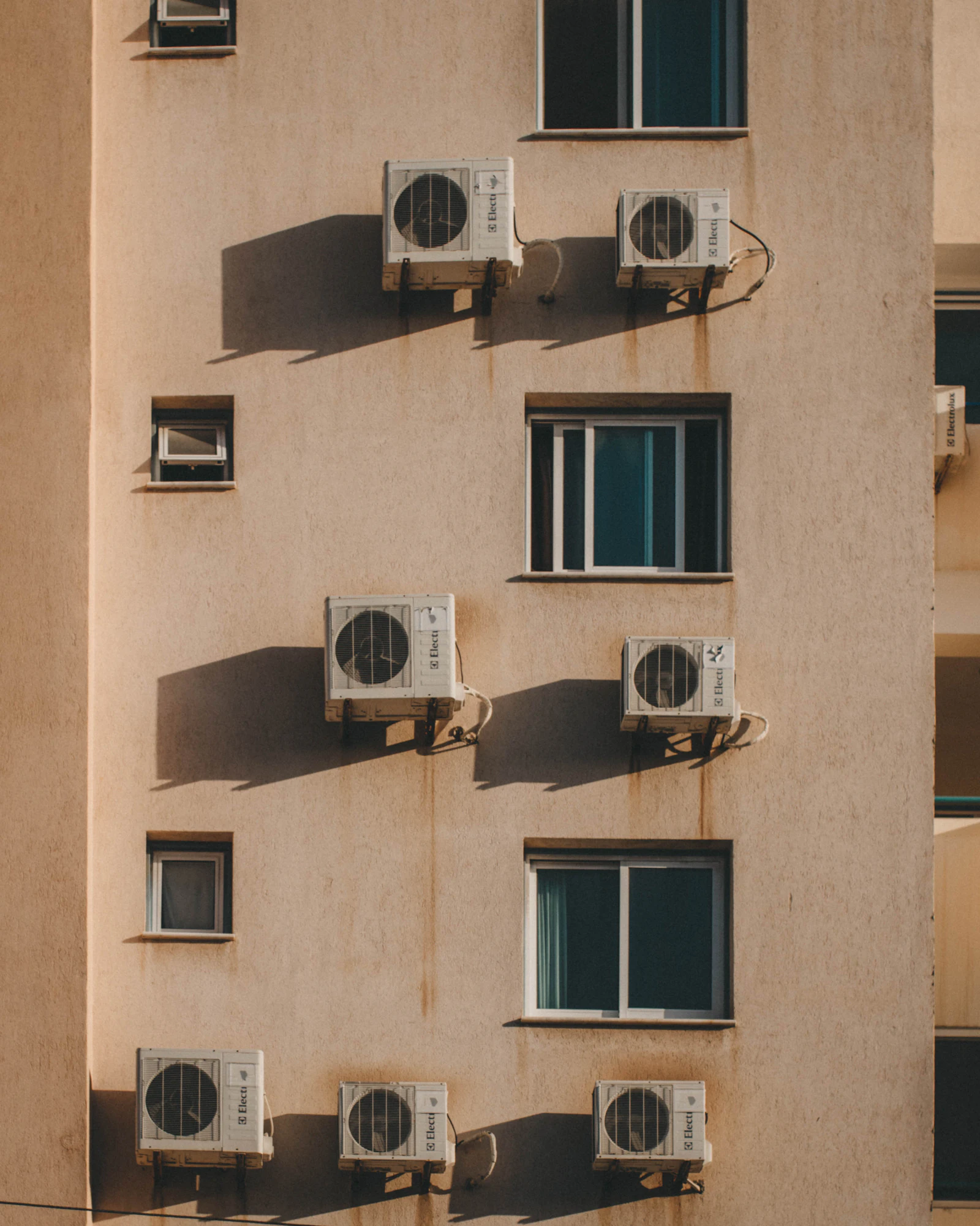 Multiple split air conditioning condenser units mounted on the exterior wall of a Gulf apartment building